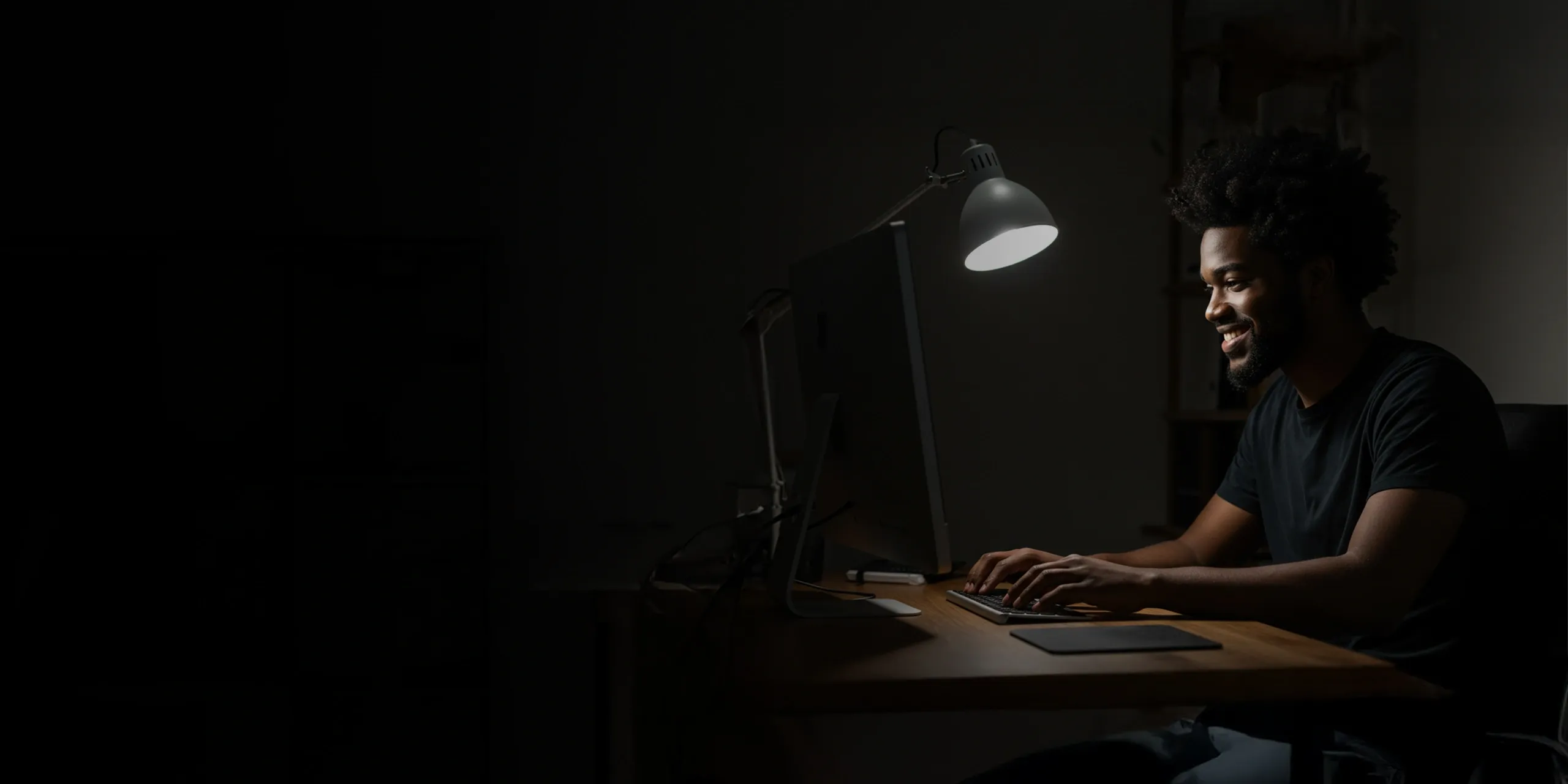 Smiling man using computer in a dark room